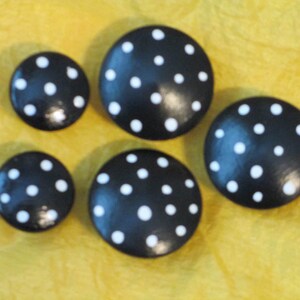 May include: Five black and white polka dot buttons. The buttons are round and have a glossy finish.