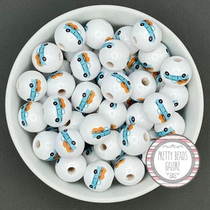 May include: A bowl filled with white wooden beads with a blue truck and orange pumpkins design. The beads are for crafting and making jewelry.