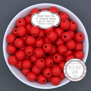 May include: A bowl filled with red round beads with a ribbed texture. The beads are approximately 20mm in diameter. The text on the label reads: "Ships Same Day if ordered before 1pm ET Mon-Fri (except on holidays)". The text on the sticker reads: "Pretty Beads Galore".