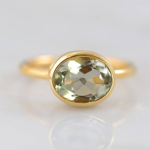 May include: A gold ring with a light green oval gemstone.