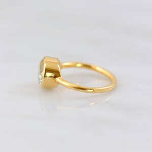 May include: A gold ring with a clear oval-shaped gemstone set in a bezel setting.