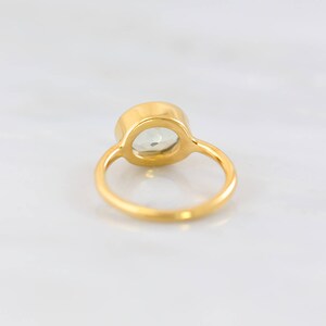 May include: A gold ring with a clear oval-shaped gemstone set in the centre.