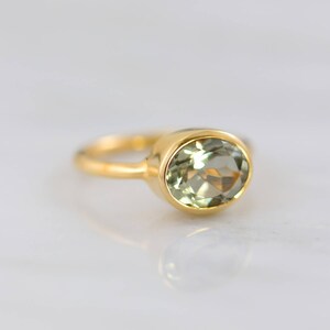 May include: A gold ring with a light green oval gemstone.