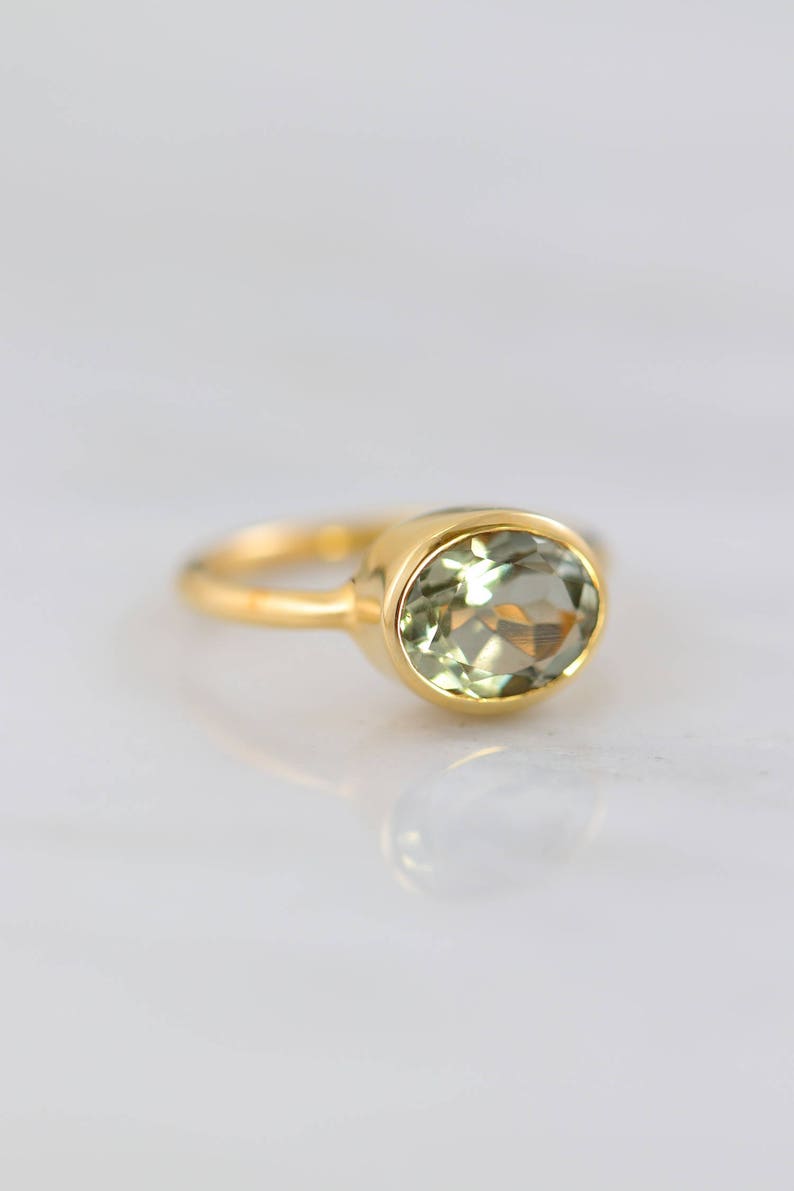 May include: A gold ring with a light green oval gemstone.