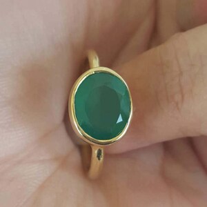 Puede incluir: Un anillo de oro con una gran piedra preciosa ovalada verde.