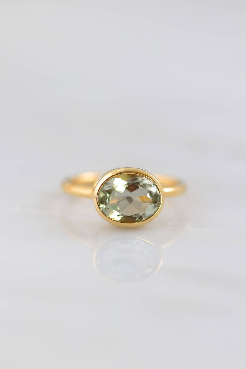 May include: A gold ring with a light green oval gemstone.