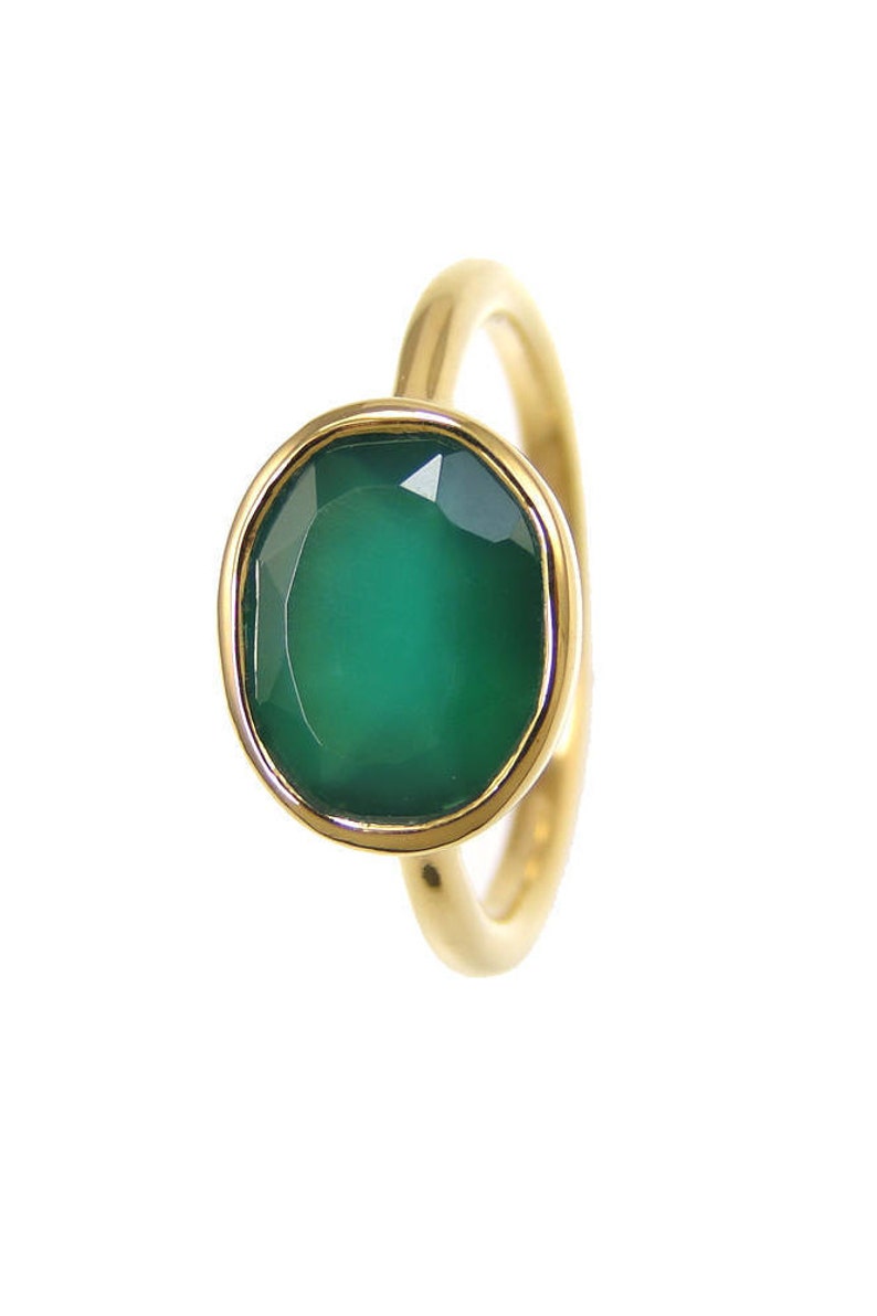 Puede incluir: Un anillo de oro con una piedra ovalada verde.