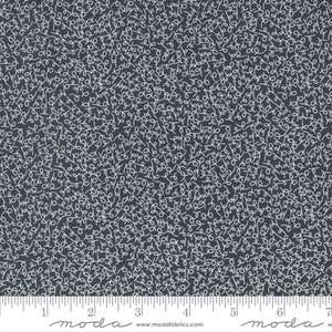 May include: A black fabric with a white scribble pattern. The fabric is marked with a ruler in inches and the words "moda" and "www.modafabrics.com".