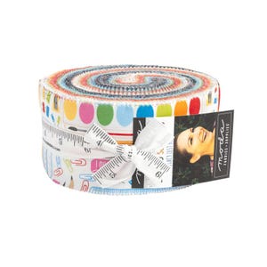 May include: A rolled fabric bundle with a colorful array of patterned strips. The bundle is wrapped with a white ribbon featuring inch measurements. A tag with the text "moda FABRICS + SUPPLIES" is attached.