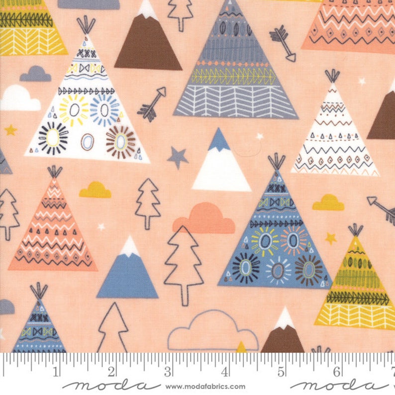May include: Peach-coloured fabric with a repeating pattern of colourful teepees, mountains, trees, and clouds. The fabric has a ruler printed at the bottom with the word "moda" printed on it.