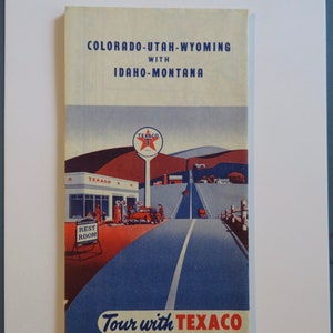 May include: A vintage Texaco road map for Colorado, Utah, Wyoming, Idaho, and Montana. The map features a red, white, and blue illustration of a Texaco gas station with a car driving down a road. The text "Tour with Texaco" is printed in red and blue.