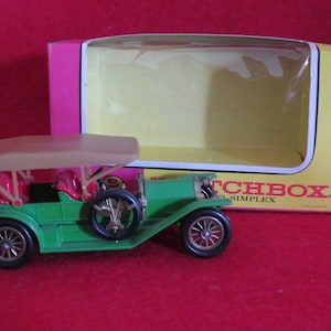 May include: A green toy car with a tan fabric top and red seats. The car is in a box that says "Matchbox" and "1912 Simplex".