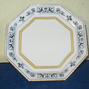 May include: Octagonal white ceramic plate with a yellow border and black and white floral design.