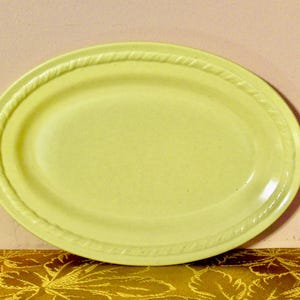 May include: A pale yellow oval serving platter with a rope-like design around the edge.