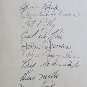May include: A white sheet of paper with a list of names written in blue ink. The names include: W Lien, Atan Dojek, Charlie Silvera, Art Lilly, Carl Dihei, John Jensen, Eddie Cham, Bil Shund, Bus mills, and Dario Fabjani.