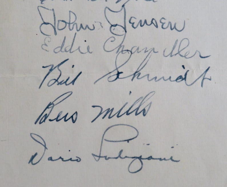 May include: A close-up of five handwritten signatures on a white piece of paper. The signatures are: John Jensen, Eddie Chazelle, Bill Schmidt, Leo Mills, and Dario Faligiani.