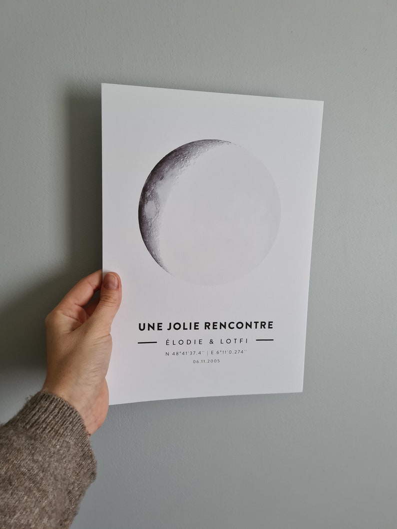 May include: A black and white print with a crescent moon graphic. The text "UNE JOLIE RENCONTRE &Eacute;LODIE & LOTFI N 48&deg;41'37.4" E 6&deg;11'0.274" 06.11.2005" is printed below the moon.