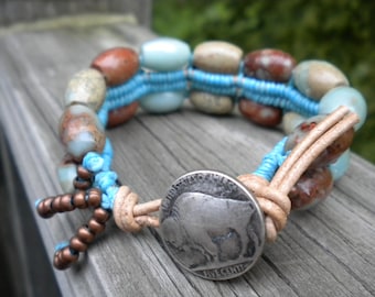Può includere: Un braccialetto di perline turchesi e marroni con un cinturino in pelle e una moneta d'argento con la scritta "FIVE CENTS" su di essa.