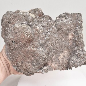 May include: A large, irregularly shaped rock with a rough, textured surface. The rock is a mottled brown and gray color with hints of pink.