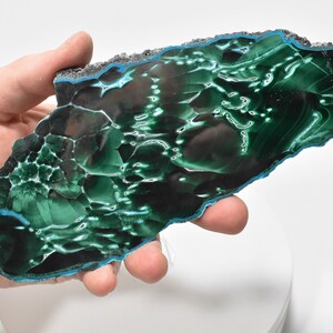 May include: A large, green and black malachite slab with a blue edge. The slab has a unique, swirling pattern.