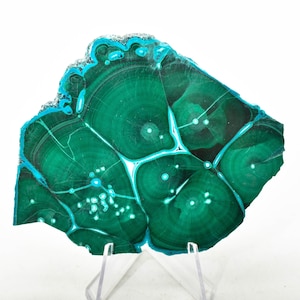 May include: A green and blue malachite stone with a swirling pattern. The stone is on a clear stand.