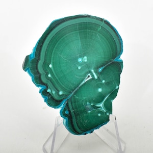 May include: A green and blue malachite stone with a swirling pattern. The stone is on a clear stand.