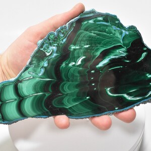 May include: A large, green and blue malachite slab with a swirling, banded pattern. The slab is polished and has a smooth, glossy finish.