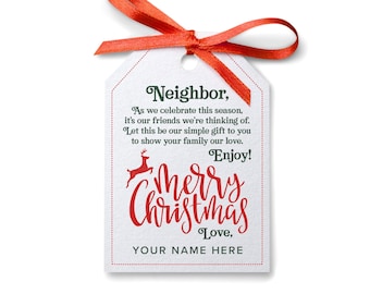 Pode incluir: Uma etiqueta de presente branca com uma fita vermelha amarrada em volta. A etiqueta tem um design verde e vermelho com o texto "Neighbor, As we celebrate this season, it's our friends we're thinking of. Let this be our simple gift to you to show your family our love. Enjoy! Merry Christmas Love, YOUR NAME HERE".