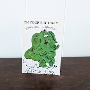 Carte de voeux d'anniversaire des années 1970 avec un éléphant vert écrasant un gâteau vintage pour des cadeaux uniques et insolites !