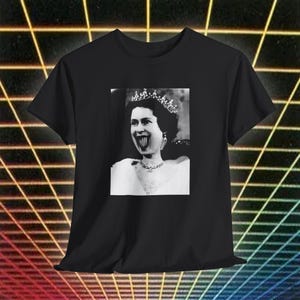 May include: Black t-shirt featuring a black and white image of a person wearing a crown and necklace with a distorted mouth. The image is centered on the front of the shirt. The background has a retro neon grid design.