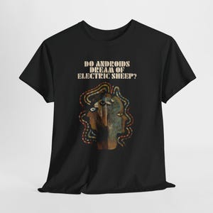 May include: Black t-shirt featuring the text "DO ANDROIDS DREAM OF ELECTRIC SHEEP?" above a graphic of a face with multiple eyes and colorful wiring. The design has a vintage, retro aesthetic.