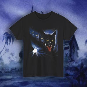 May include: Black t-shirt featuring a spooky graphic of black cats with glowing yellow eyes and open mouths, with a full moon in the background. The design has a dark, eerie aesthetic, perfect for Halloween or cat lovers.