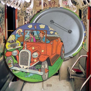 May include: A vintage button featuring a cartoon illustration of three people in a red car. The car has a yellow license plate that reads "518". The button is round and has a silver back.