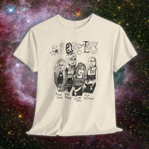 May include: Cream-colored t-shirt featuring a black and white illustration of the band The Bangles. The band's name is written above the illustration, with the names of the band members below.