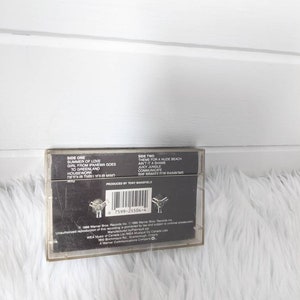May include: A black cassette tape with the title "Summer of Love" and the artist "Wig" printed on the front. The back of the tape lists the songs on each side, including "Theme for a Nude Beach" and "Ain't It a Shame".