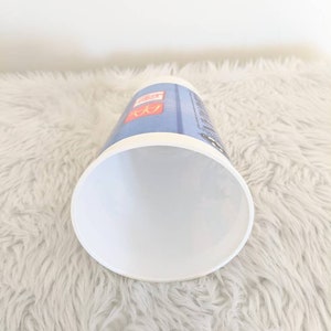 May include: White disposable cup with a blue and red design. The cup has the McDonald's logo and the text "McCafe" printed on it.