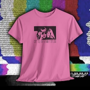 Puede incluir: Camiseta rosa con un gráfico negro de una mujer con gafas de sol y un cigarrillo. El texto "DON'T TELL MOM THE BABYSITTER'S DEAD" está impreso debajo. Cuello redondo, mangas cortas.