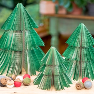 May include: Three green paper Christmas trees of varying sizes decorated with red, white, and brown felt ornaments. The trees are made from folded pages of a book.