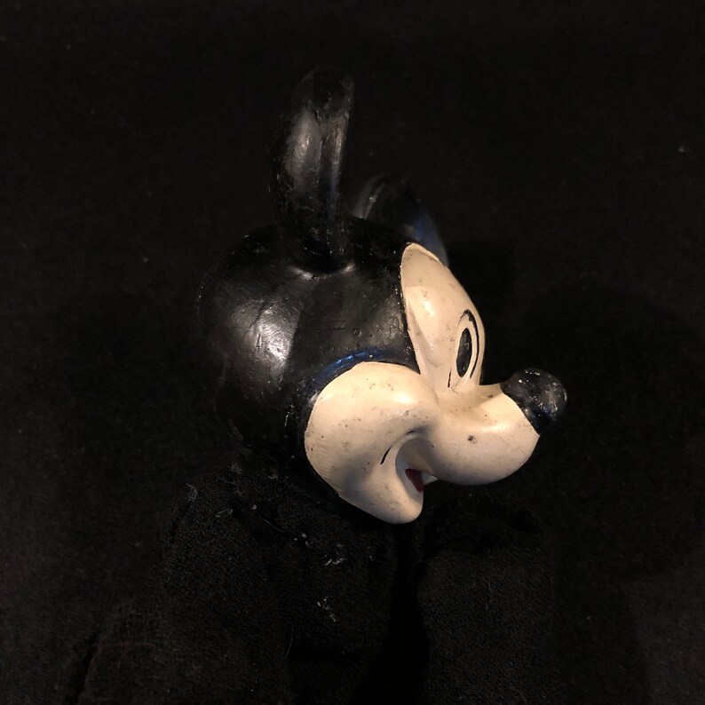 Puede incluir: Primer plano de un juguete de peluche vintage de Mickey Mouse en blanco y negro. El juguete tiene un cuerpo de fieltro negro y una cara blanca con ojos negros y una boca roja.