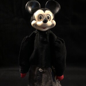 Puede incluir: Un t&iacute;tere vintage de Mickey Mouse en blanco y negro con un cuerpo de fieltro negro y manos de fieltro rojo. El t&iacute;tere tiene una cabeza grande con una cara blanca y ojos negros.