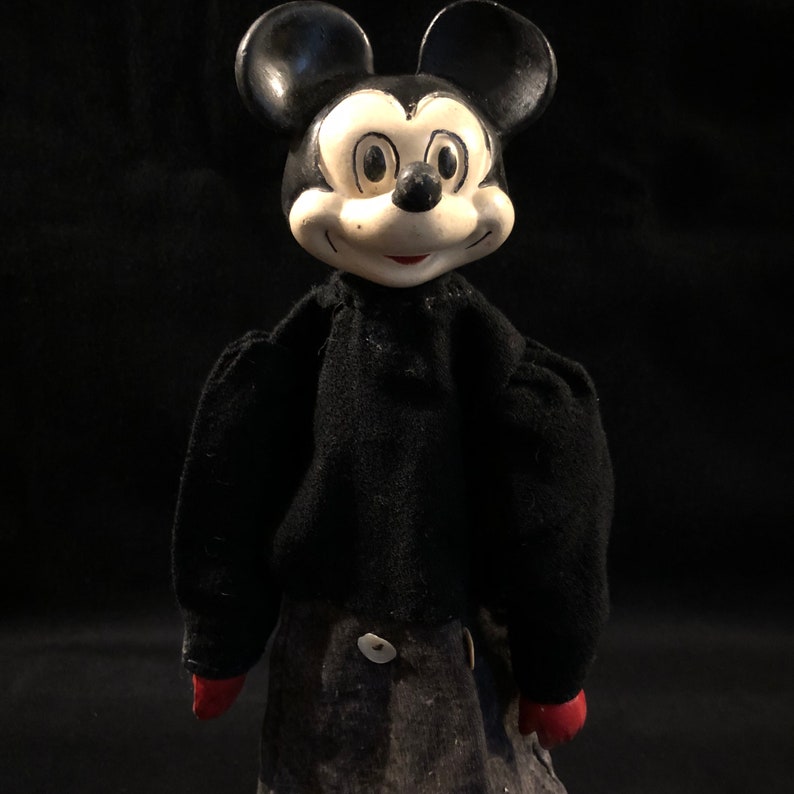 Puede incluir: Un t&iacute;tere vintage de Mickey Mouse en blanco y negro con un cuerpo de fieltro negro y manos de fieltro rojo. El t&iacute;tere tiene una cabeza grande con una cara blanca y ojos negros.