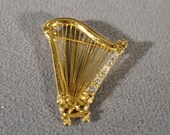 vintage gold tone pin brooch in a harp design with round faceted white rhinestones M10