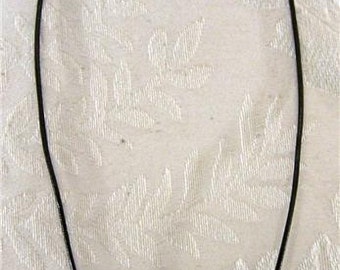 May include: A black leather cord necklace with a silver cross pendant featuring a small gold gemstone in the center.