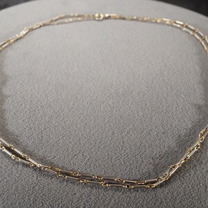 May include: A double-strand necklace with a delicate chain made of alternating silver and gold links.