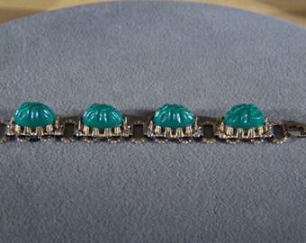 May include: A silver chain bracelet with four green cabochon stones. The stones are set in silver and have a carved design.