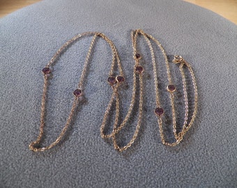 May include: A gold chain necklace with multiple strands and small purple gemstones.