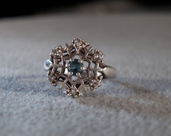 May include: A silver ring with a snowflake design and a blue gemstone in the center.