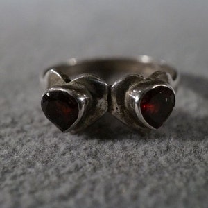 May include: A silver ring with two heart-shaped red gemstones.