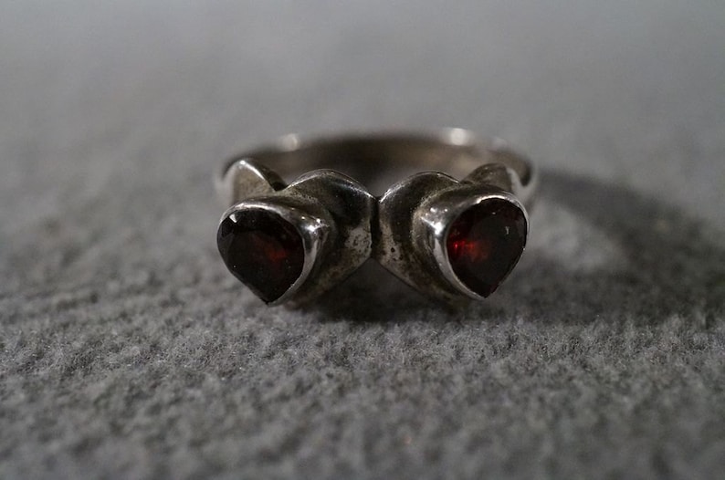 May include: A silver ring with two heart-shaped red gemstones.
