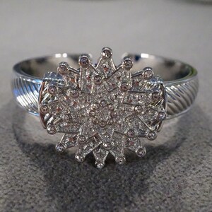 May include: Silver bangle bracelet with a large, sparkly, star-shaped design.